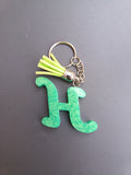 Porte-clé lettre H sculptée en résine vert émeraude effet marbre nacré avec pompon suédine vert anis fluo et chaînette argentée
